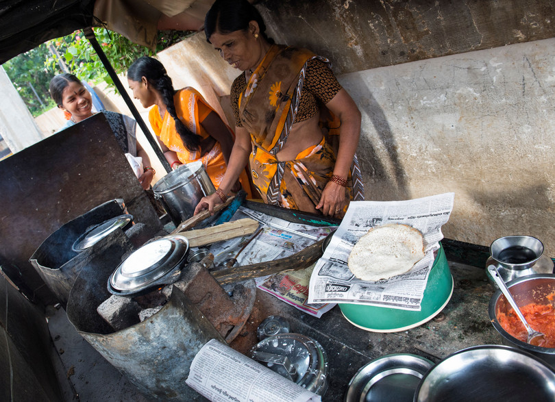 Indian woman cooking dosas for people on the street in Andhra Pradesh, India.