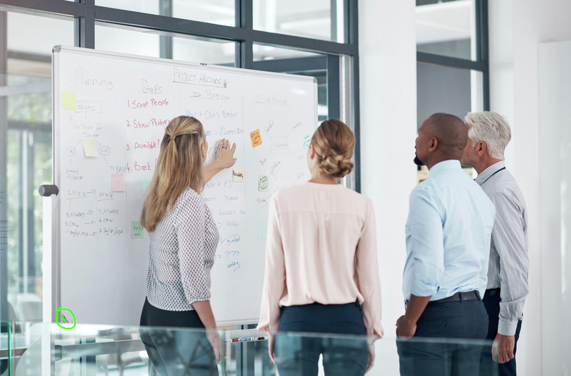 A group of business people working together at a whiteboard.