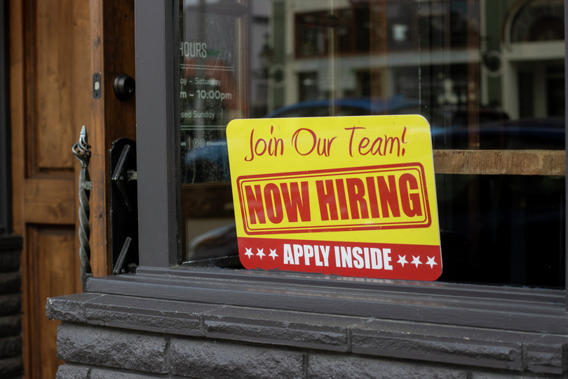 Now Hiring sign at the storefront of a local business in Salem, Oregon.