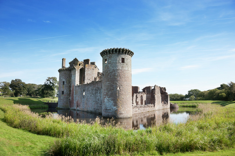 A castle with a water-filled moat surrounding it.